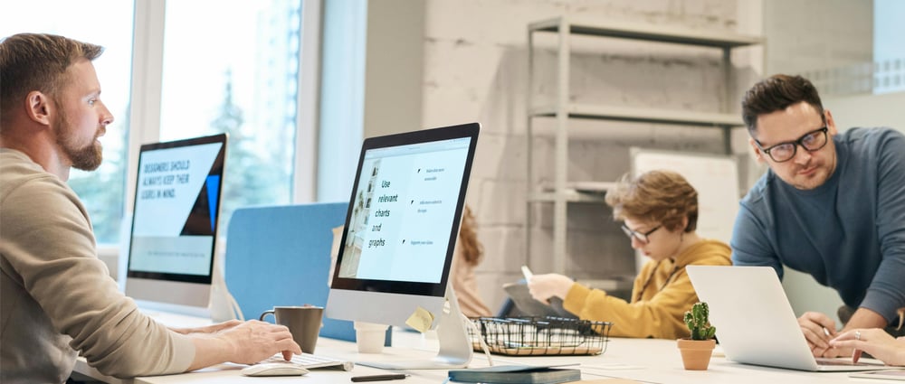 Företagsmiljö med personer som sitter framför datorer och jobbar